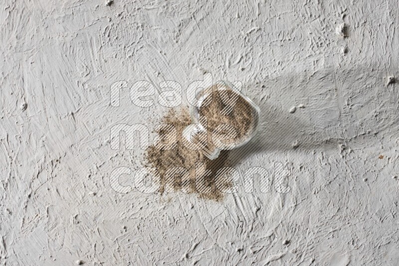 فلفل أسود مطحون في وعاء زجاجي مقلوب علي خلفية بيضاء