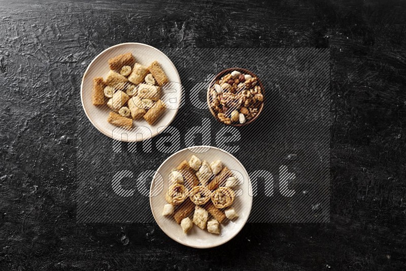 Oriental sweets in pottery plates with nuts in a dark setup