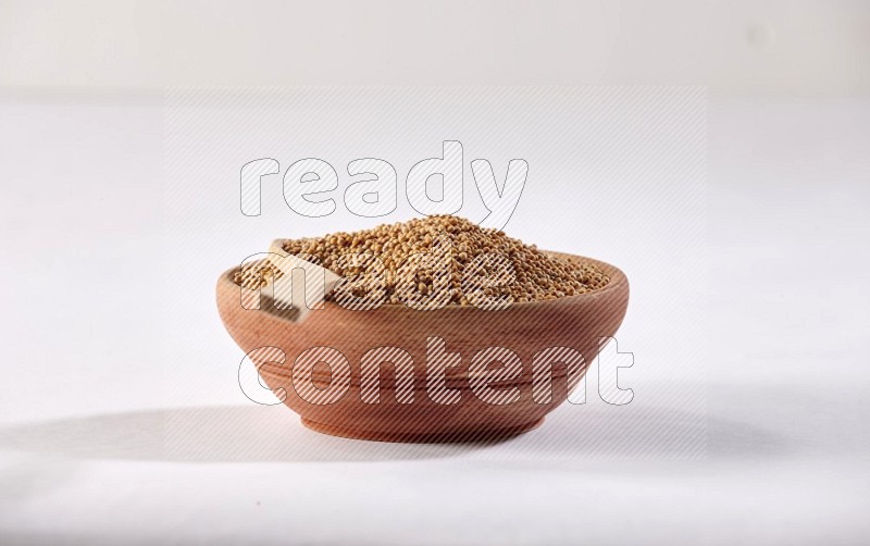 A wooden bowl and spoon full of mustard seeds on a white flooring in different angles