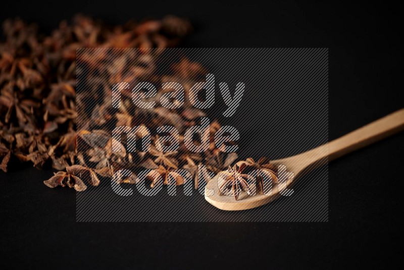 Star Anise in a wooden spoon and spreading on a black flooring