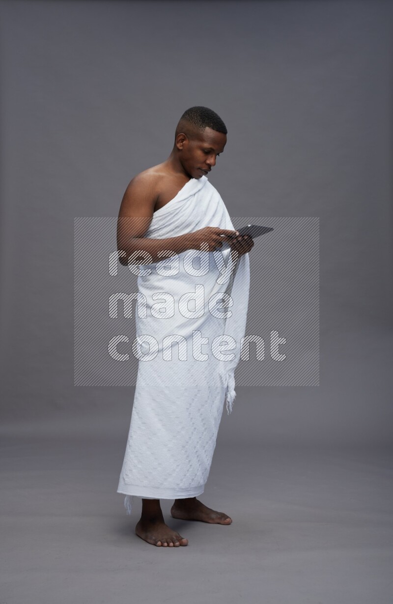 A man wearing Ehram Standing working on tablet on gray background