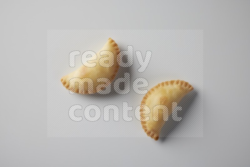 Two fried sambosa from a top angle on a white background