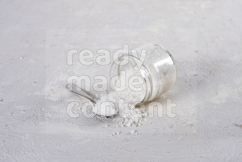 A glass jar full of coarse sea salt crystals on white background