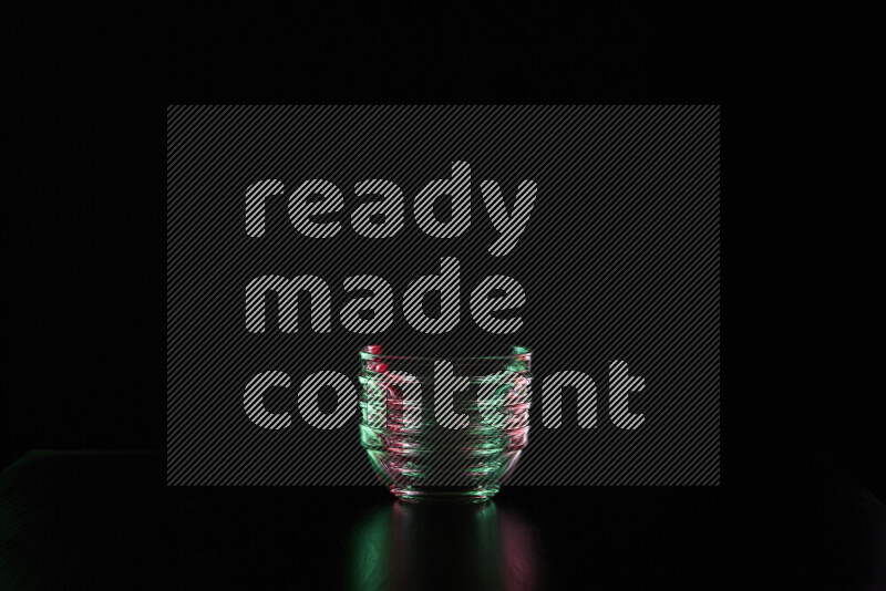 Glassware with rim light in red and green against black background