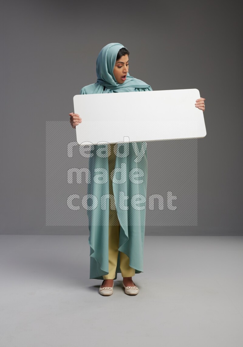Saudi Woman wearing Abaya standing holding board on Gray background