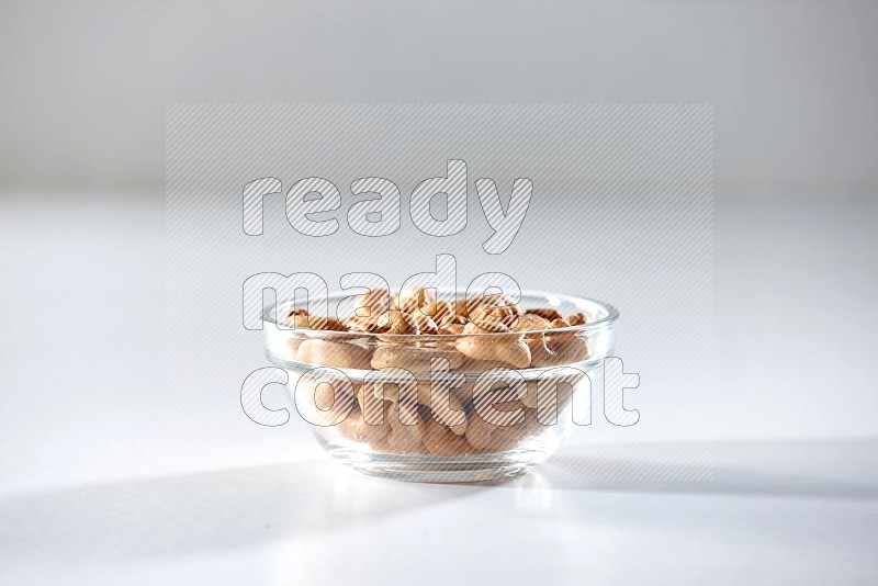 A glass bowl full of cashews on a white background in different angles