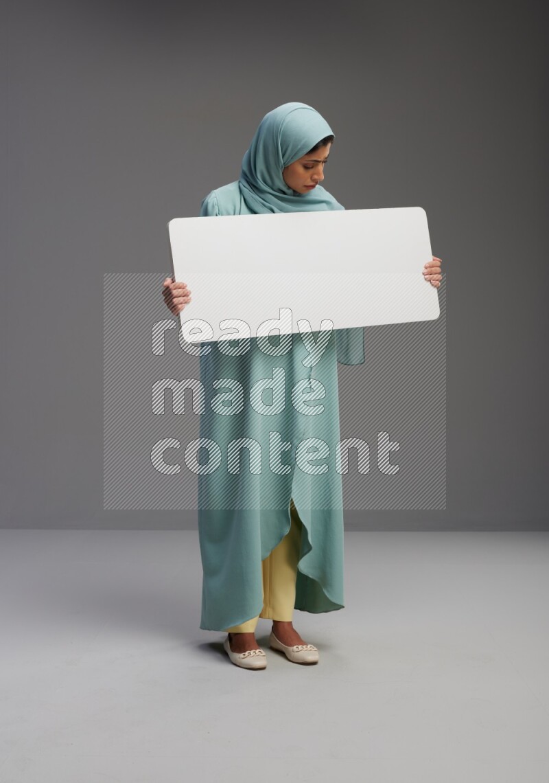 Saudi Woman wearing Abaya standing holding board on Gray background