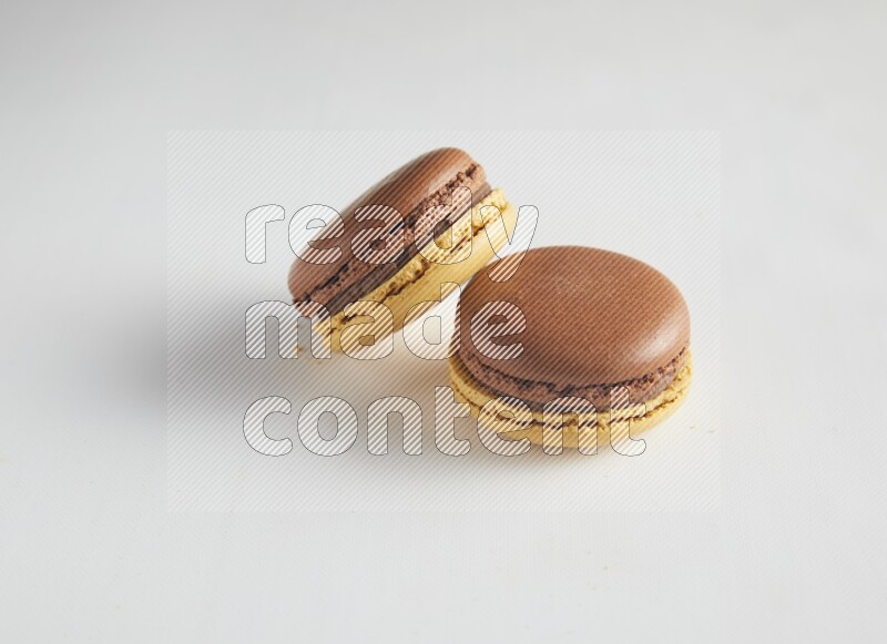 45º Shot of two Yellow and Brown Chai Latte macarons on white background