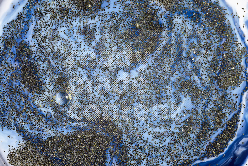 لقطة مقربة لبريق ذهبي متلألئ منتشر على خلفية من اللون الأزرق في حركات دائرية