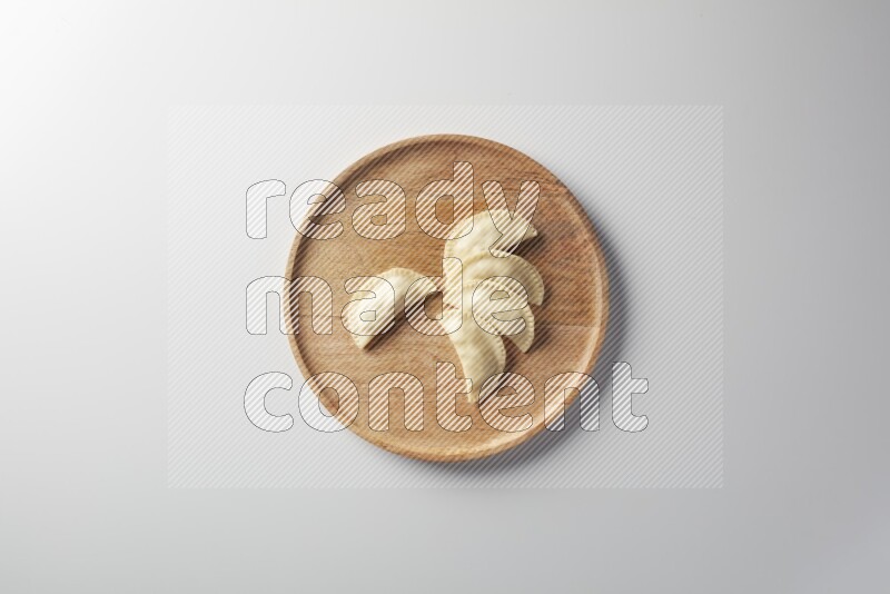 Five Sambosas on a wooden round plate on a white background