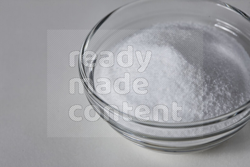 A glass bowl full of fine table salt on white background