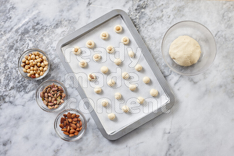 Ghoriba step by step with its ingredient, flour, powdered sugar, ghee and nuts on grey marble background