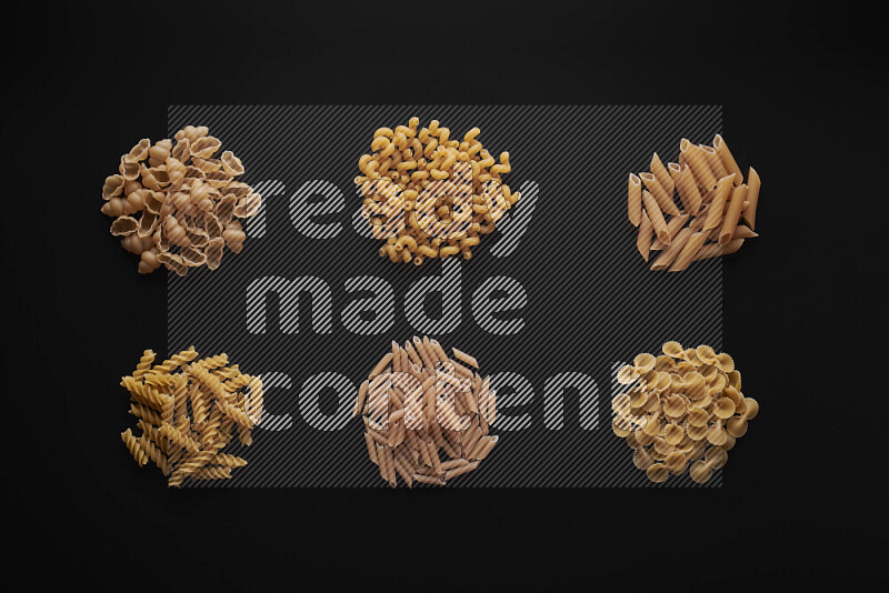 Different pasta types in bunches on black background