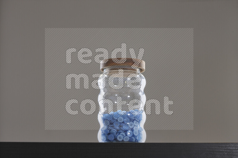 أزرار متنوعة في وعاء زجاجي علي خلفية سوداء