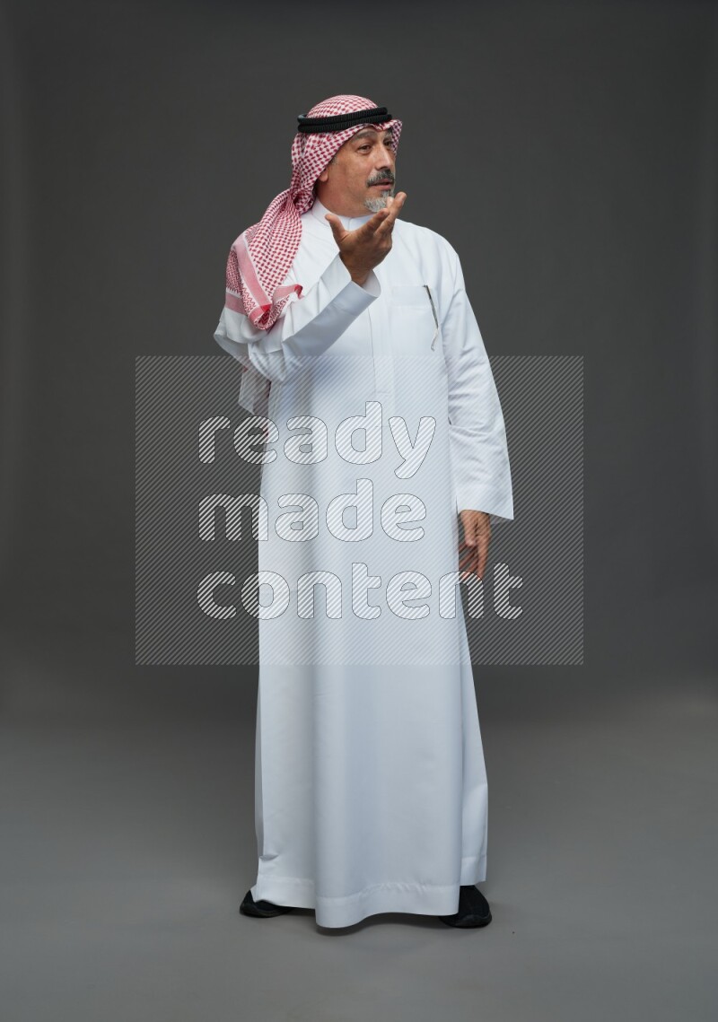 Saudi man with shomag Standing Interacting with the camera on gray background