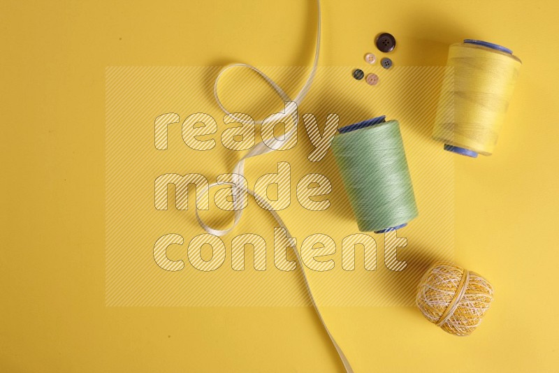 Green sewing supplies on yellow background