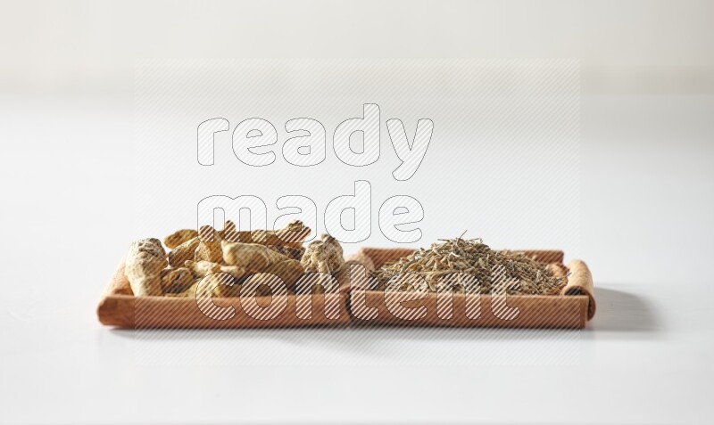 مربعان من أعواد القرفة ممتلئان بحبوب الكمون وأصابع الكركم علي خلفية بيضاء