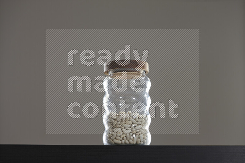 White beans in a glass jar on black background