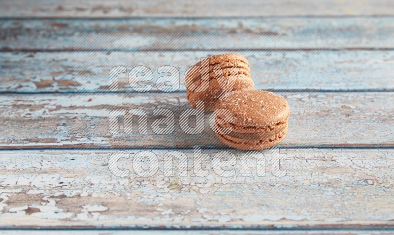 45º Shot of two Brown Hazelnuts macarons on light blue wooden background