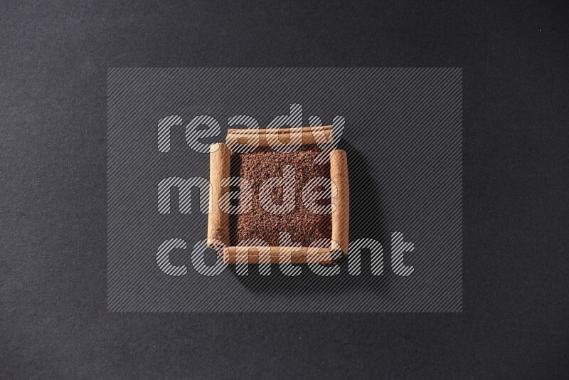 A single square of cinnamon sticks full of garden cress on black flooring