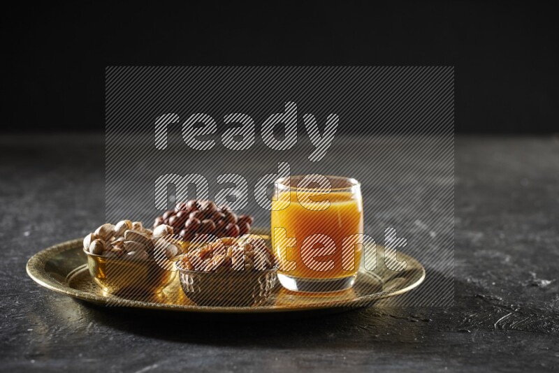 Nuts in metal bowls with qamar eldin on a tray in dark setup