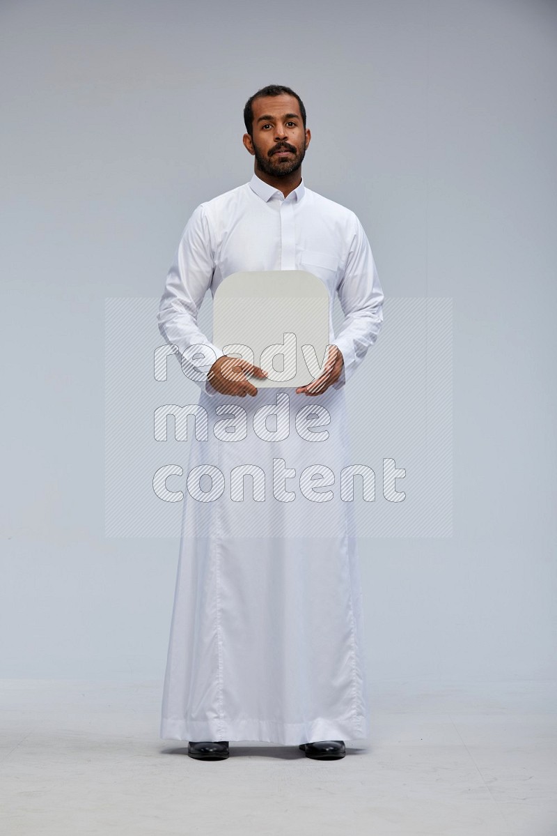 Saudi man wearing Thob standing holding social media sign on Gray background