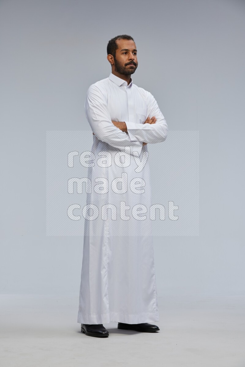 Saudi man wearing Thob standing with crossed arms on Gray background