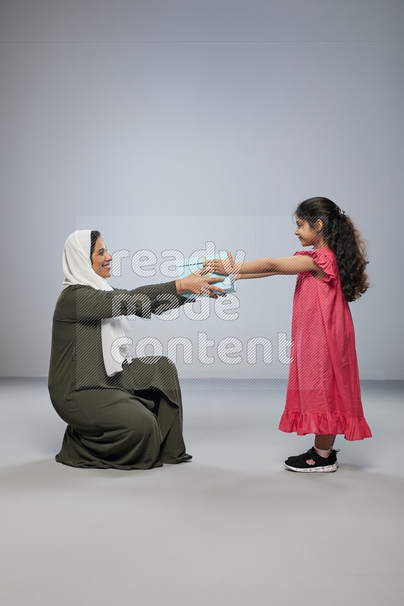 A girl giving a gift to her mother on gray background