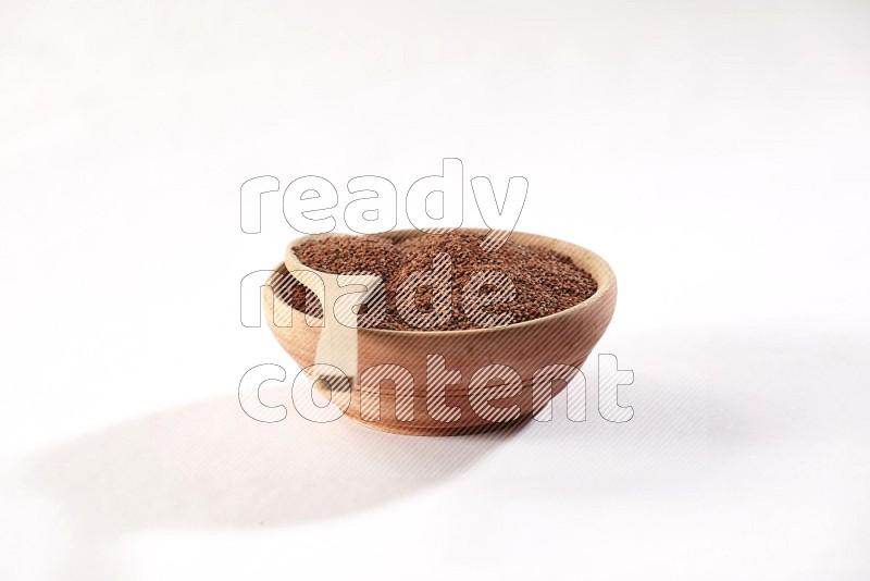 A wooden bowl and spoon full of garden cress seeds on a white flooring