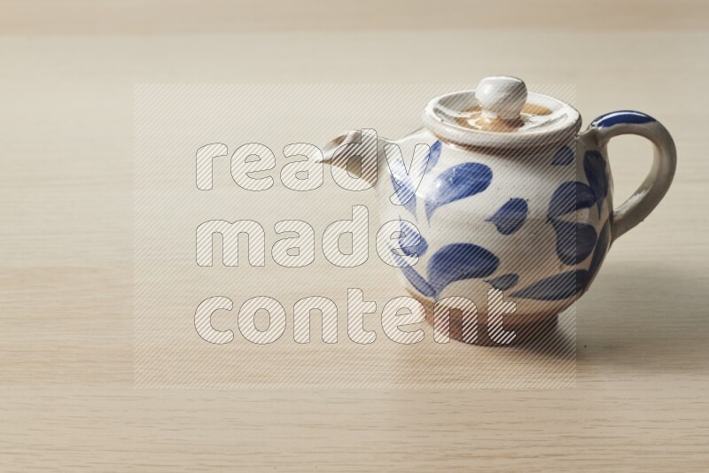 A pottery teapot on light wooden background