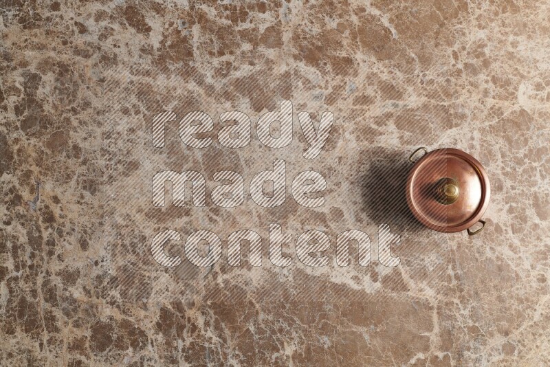 A small copper pot on beige marble background