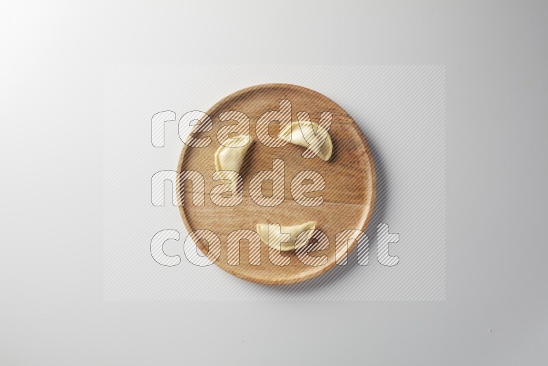 Three Sambosas on a wooden round plate on a white background