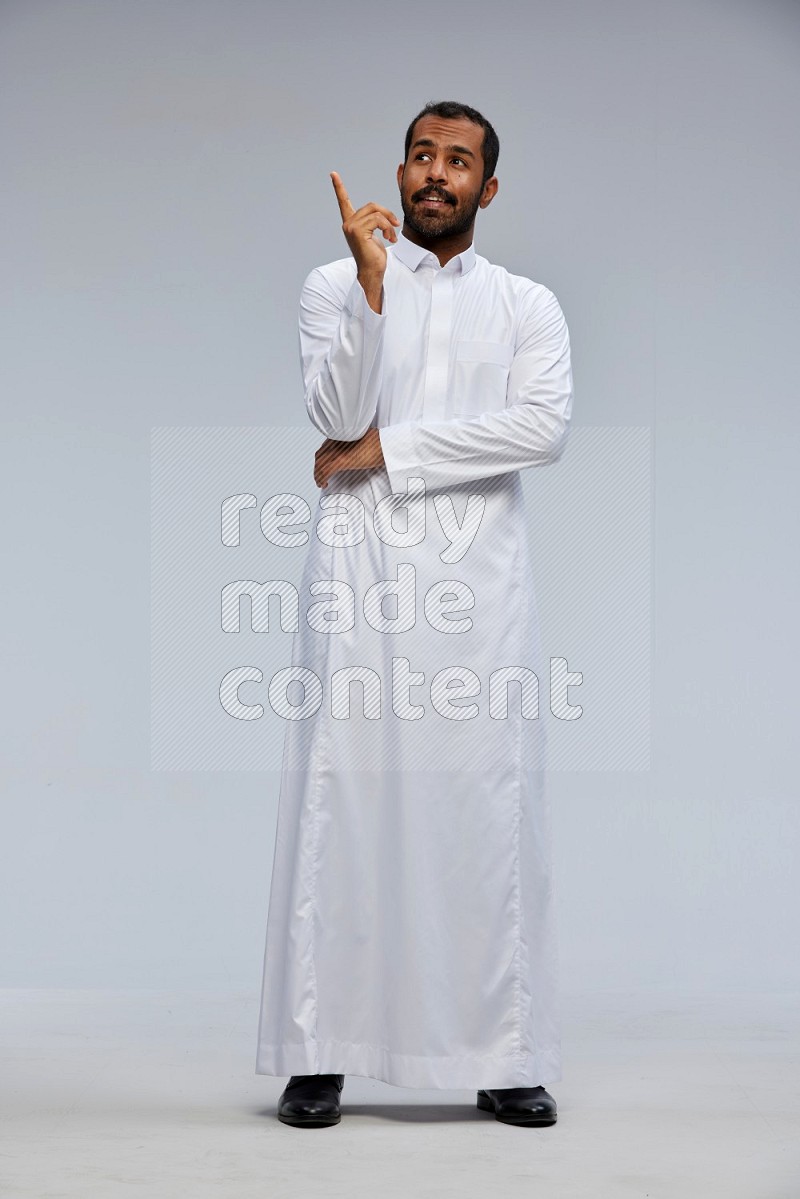 Saudi man Wearing Thob standing interacting with the camera on Gray background