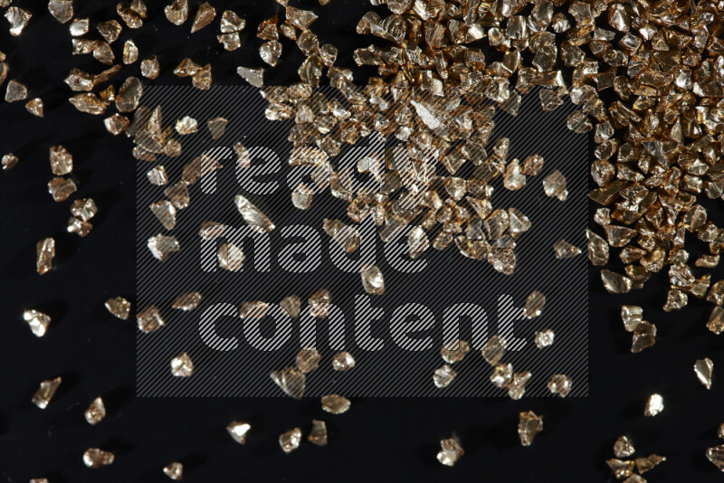 Gold shimmering fragments of glass scattered on a black background