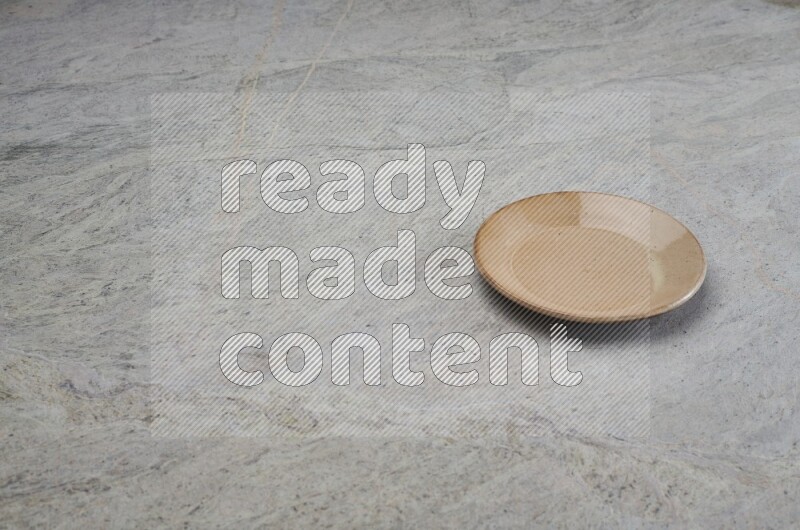 A beige pottery plate on grey marble background