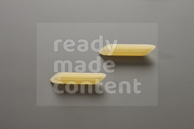 Mini penne pasta on grey background