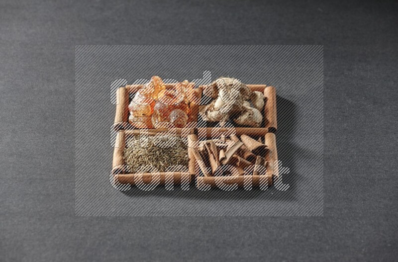 4 squares of cinnamon sticks full of gum arabic, dried ginger, cinnamon and cumin on black flooring