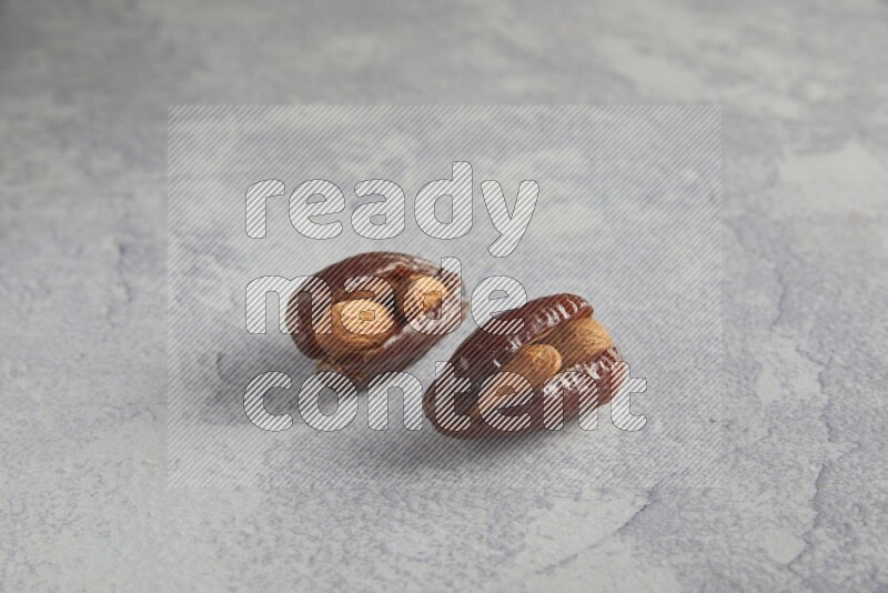 Two Almond stuffed date on a light grey background