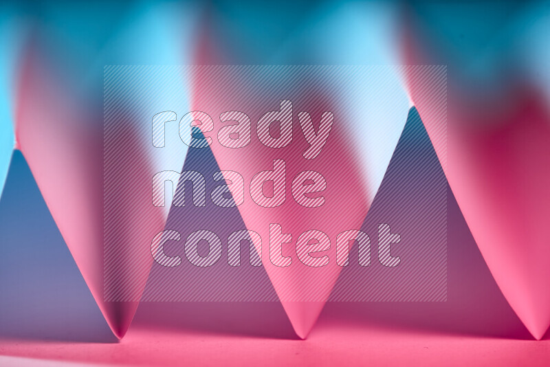 A close-up abstract image showing sharp geometric paper folds in blue and red gradients