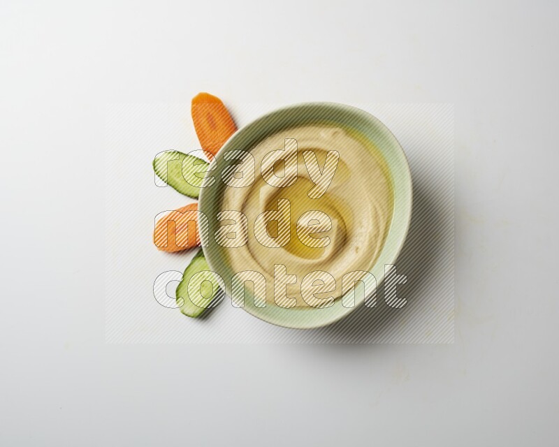 Hummus in a green plate garnished with olive oil on a white background