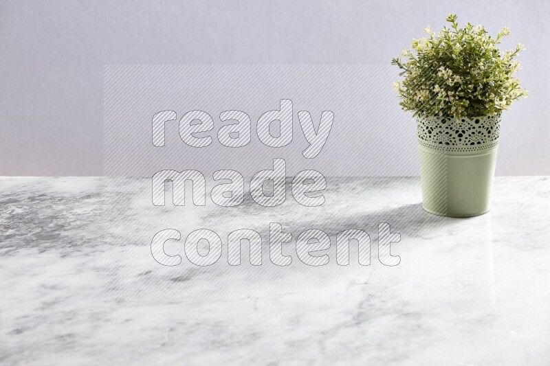 Artificial plant in green decorative pot on grey marble background