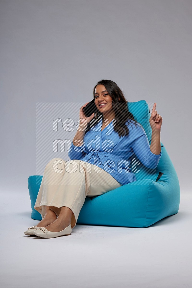 A woman sitting on a blue beanbag and talking on the phone