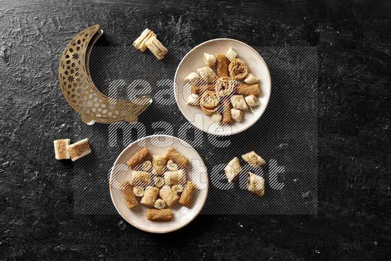 حلويات شرقية في أطباق فخارية مع فانوس خشبي علي خلفية خشبية