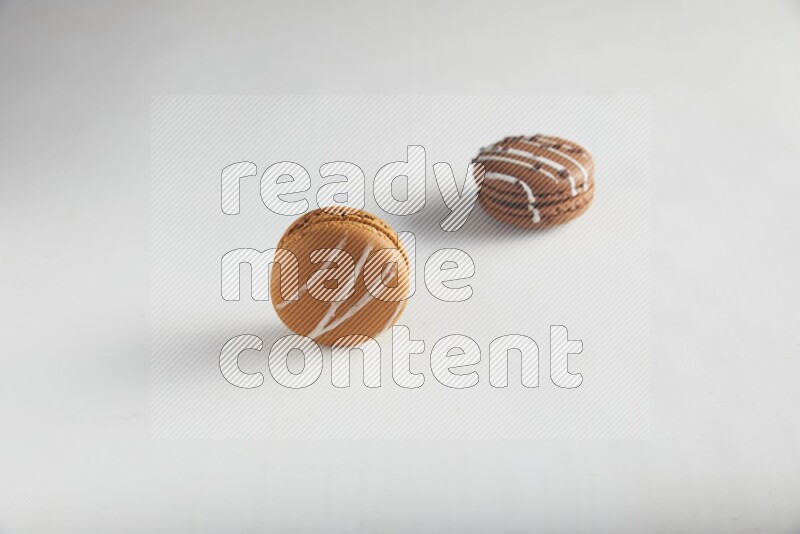 45º Shot of of two assorted Brown Irish Cream, and Brown white Chocolate Caramel macarons on white background