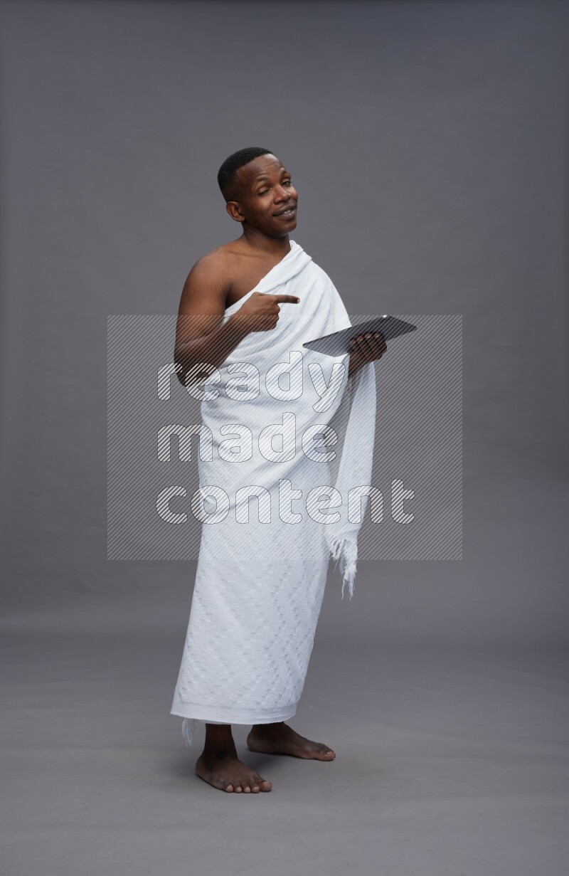 A man wearing Ehram Standing working on tablet on gray background