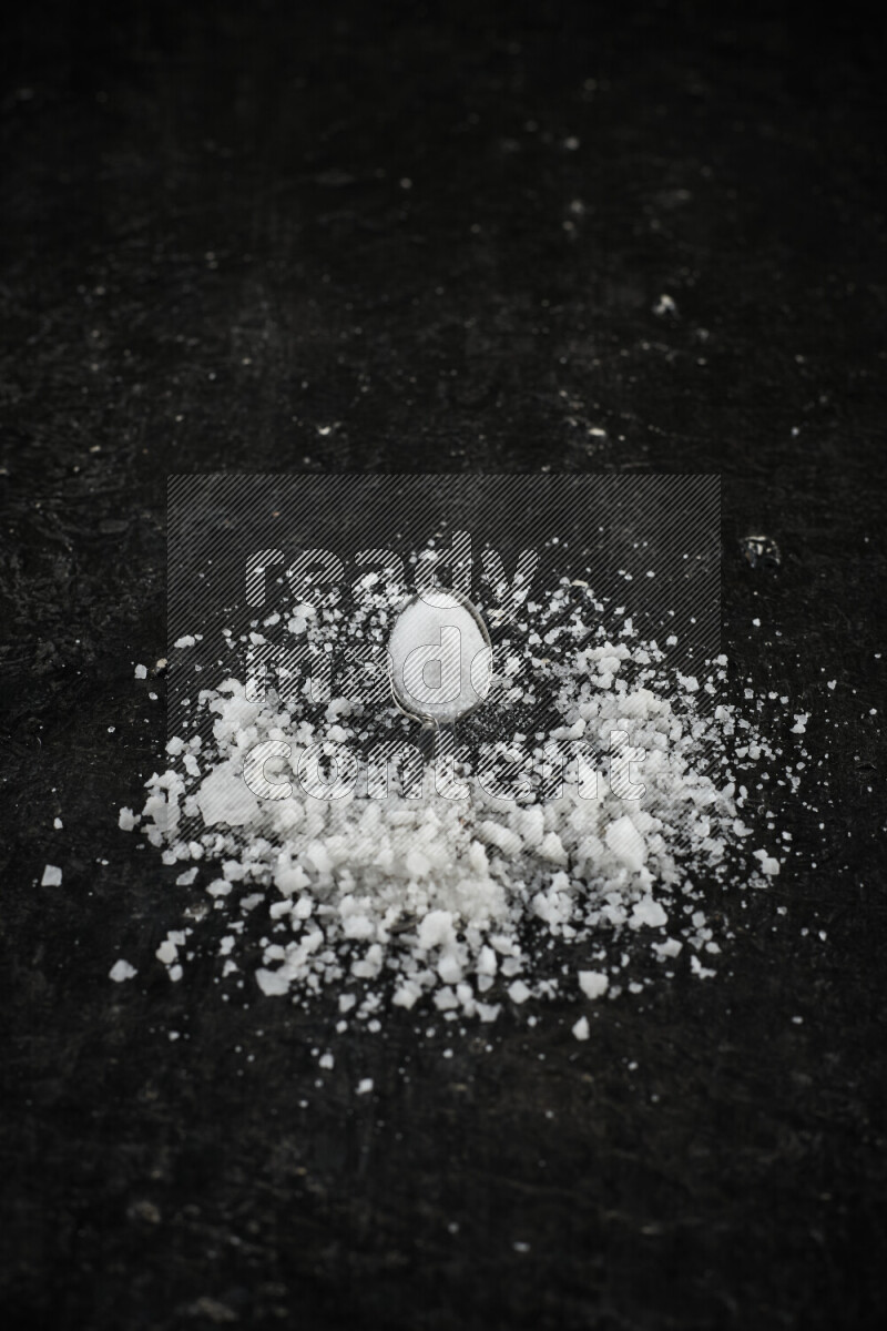 ملعقتان معدنيتان ممتلئتان بالملح الأبيض على خلفية سوداء