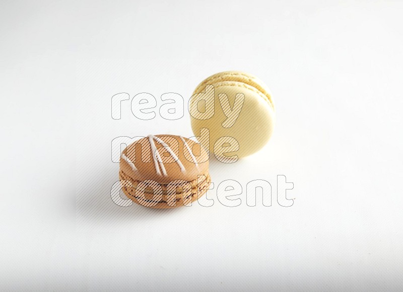 45º Shot of of two assorted Brown Irish Cream, and Yellow Vanilla macarons on white background