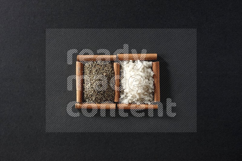 2 squares of cinnamon sticks full of white salt and cumin on black flooring