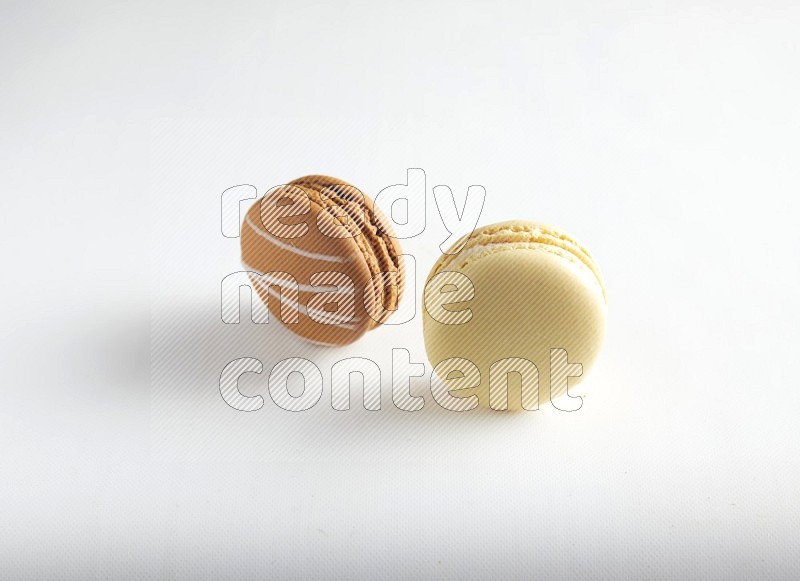 45º Shot of of two assorted Brown Irish Cream, and Yellow Vanilla macarons on white background