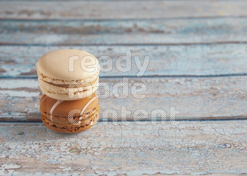 45º Shot of of two assorted Brown Irish Cream, and White Caramel fleur de sel macarons on light blue background